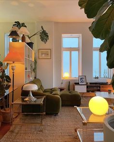 a living room filled with lots of furniture and plants on the wall next to windows