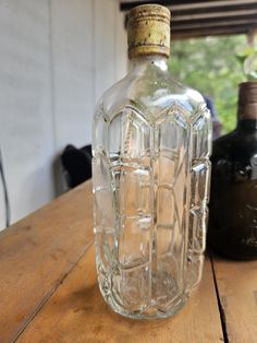 an empty glass bottle sitting on top of a wooden table