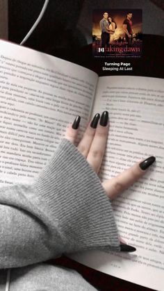 a woman with black nails is reading a book