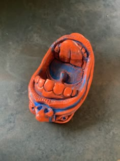 an orange and blue object sitting on top of a cement floor next to a wall