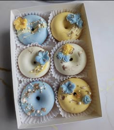 six decorated doughnuts in a box on a table