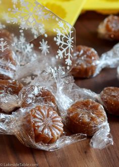 some candies are wrapped in plastic on a wooden table with snowflakes around them