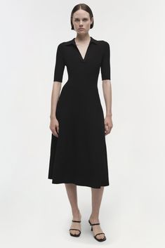 SIGNATURE COLLECTION The Signature Pati Dress in Black. Featuring a flattering V-neck collar and ribbed texture, this midi piece gracefully flows, encapsulating timeless elegance with a modern twist. Ideal for both daywear and evening occasions.