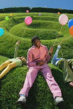 two people laying in the grass with balloons