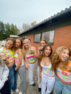 a group of young women standing next to each other in front of a brick building