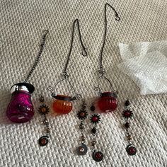 five different colored glass items on a white surface next to a pair of silver earwires