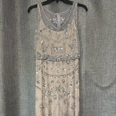 a dress hanging on a hanger in front of a gray curtain with silver sequins