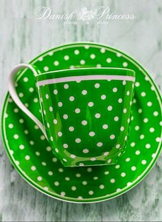 a green cup and saucer with white polka dots