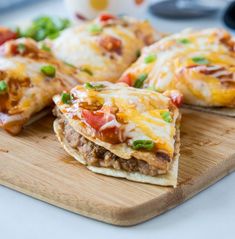 several pieces of pizza sitting on top of a wooden cutting board with cheese and other toppings