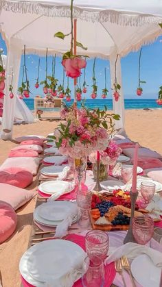 a table set up on the beach with plates and utensils