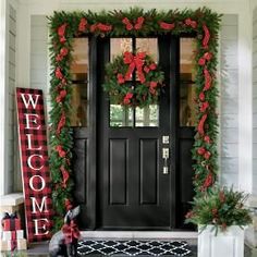 a black front door decorated for christmas with wreaths and decorations on the side porch