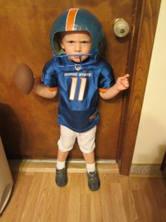 a young boy wearing a football uniform standing in front of a door