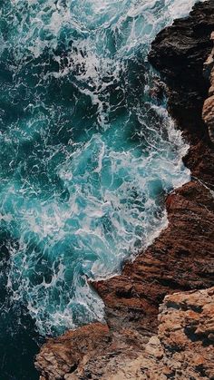 an ocean view with waves crashing on the rocks