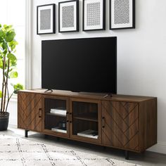 a flat screen tv sitting on top of a wooden entertainment center next to a potted plant