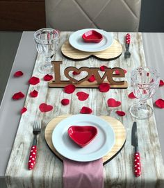 the table is set with plates and silverware for valentine's day dinner in spanish