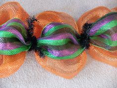 two orange mesh hair bows with green and purple stripes