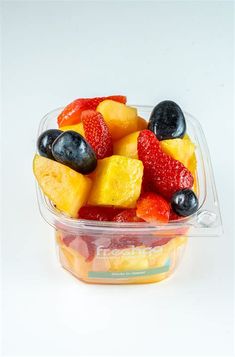 a plastic container filled with fruit on top of a white table