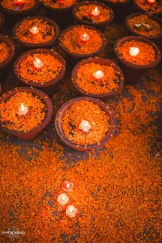 candles are placed in clay pots on the ground with orange sprinkles around them