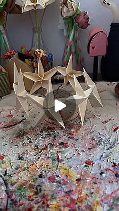 an origami sculpture sitting on top of a table covered in paint and paper