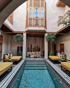 an indoor swimming pool with yellow lounge chairs and potted trees in the corner area