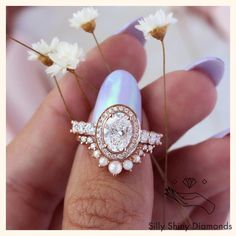 a woman's hand holding two rings with flowers in front of her and the other ring