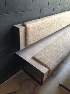 a pair of benches sitting next to each other on top of a cement floor in front of a brick wall