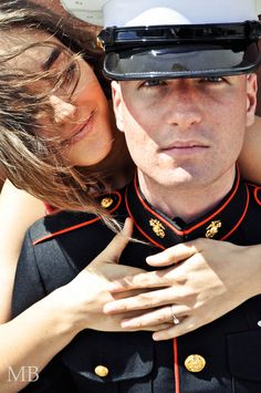 a man in uniform is hugging a woman's neck with his arms around her