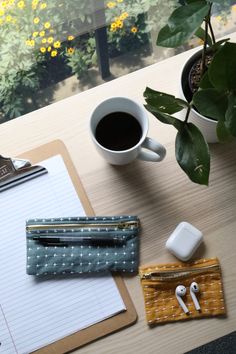 a desk with a notepad, pen and headphones next to a cup of coffee