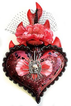 a red heart shaped decoration with flowers on it's side and a skull in the middle