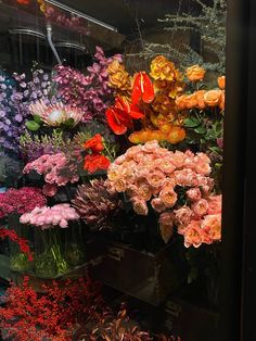 many different colored flowers in vases on display