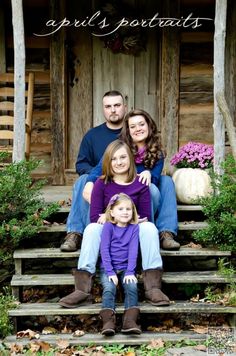 a family sitting on steps in front of a wooden building