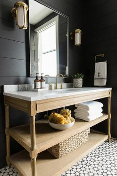 a white sink sitting under a bathroom mirror next to a wooden shelf filled with towels