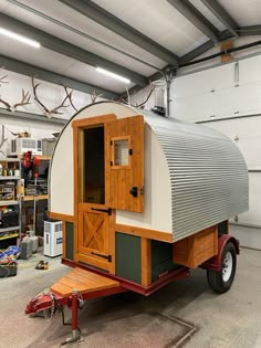 a trailer that has been converted into a tiny house with wood trimmings on the sides