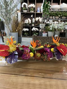 the flowers are arranged on the table in front of the vases and other plants