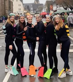 a group of young women standing next to each other on a wet street with umbrellas