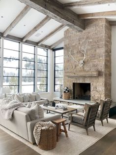 a living room filled with furniture and a fire place in front of a windowed wall