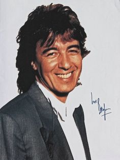 a man in a suit and tie smiling at the camera with an autograph on his face