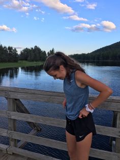 a girl standing on a bridge looking down at the water with her hands on her hips