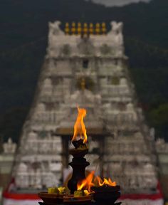 flames are lit in front of a temple