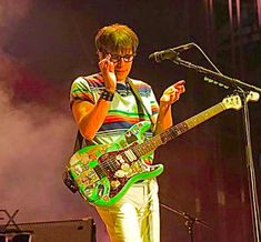 a man standing next to a microphone while holding a guitar in front of his face