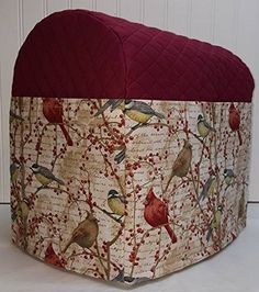 a round ottoman cover with birds and berries on it, sitting in front of a white wall