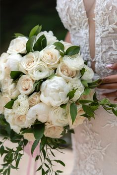 a bridal holding a bouquet of white roses and greenery in her left hand