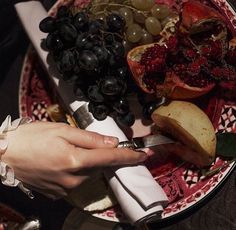 a person is cutting up some fruit on a red and white plate with silverware