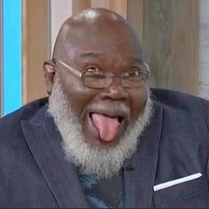 a man with his tongue out making a funny face while wearing glasses and a suit