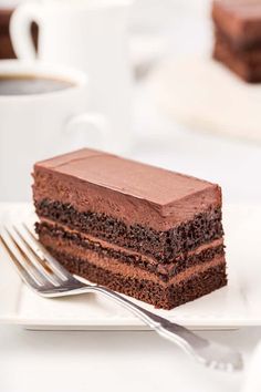 a piece of chocolate cake sitting on top of a white plate next to a fork