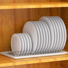 white plates and silverware are stacked on a shelf