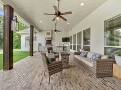 an outdoor living area with wicker furniture and ceiling fan on the side of the house