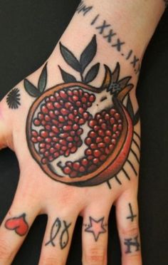 a person's hand with tattoos on it and a pomegranate tattoo