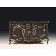 an antique black and gold painted cabinet with ornate designs on the doors, possibly from france