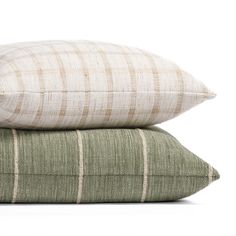 three pillows stacked on top of each other in front of a white background and one is green